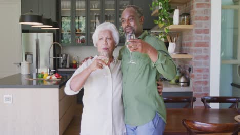 senior african american husband and mixed race wife drinking a beverage together at home