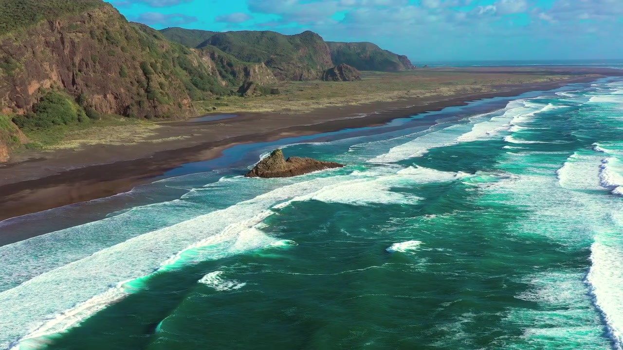 Ombak menghantam garis pantai dan tebing di taman regional Karekare, Auckland, bidikan udara