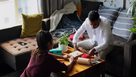 Vista-De-ángulo-Alto-De-Una-Joven-Pareja-Asiática-Empacando-Una-Caja-De-Regalo-En-La-Sala-De-Estar-De-Casa-4k