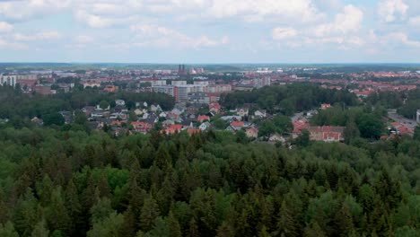 wide aerial dolly left showing city eskilstuna from afar with lush forrest in foreground