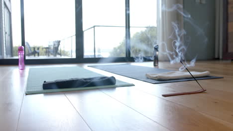 close up of yoga mats, water bottles and incense on floor, slow motion