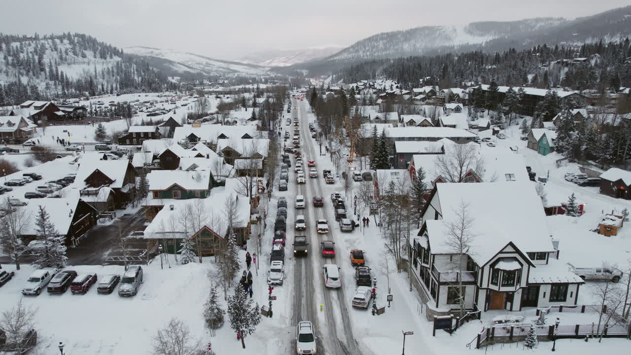 Dynamic aerial of cars carrying skis and snowboards in winter, driving into a snow covered Breckenridge, the popular Colorado mountain town for a ski vacation at the world famous resort.