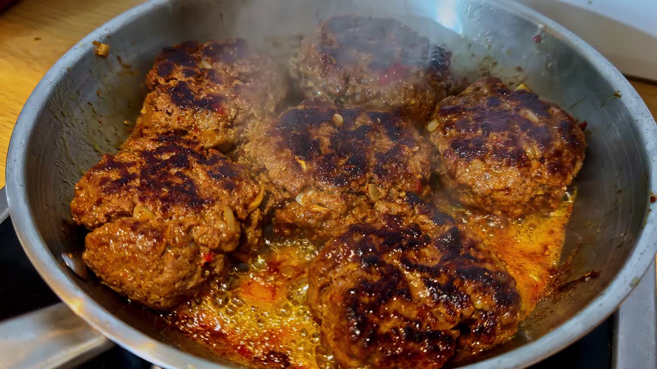 Lähikuva höyryävästä padasta, jossa lihaa, sipulipullia, perinteistä kotitekoista lohturuokaa valmistumassa