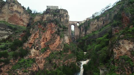 aerial 4k drone pan up reveal toward waterfall and puente nuevo bridge in ronda, andalusia, spain