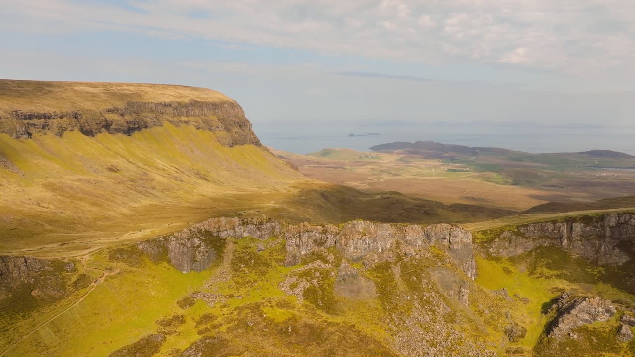 Aerial drone footage of the dramatic mountain landscapes on the Isle of Skye, Scotland. Sweeping panoramic views of majestic peaks, green valleys, and wild nature. Quiraing walk