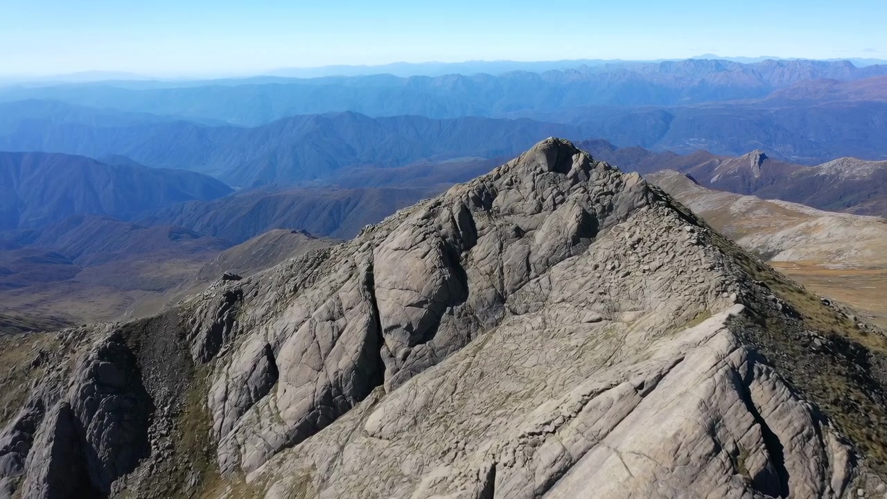Vista Aerea: Vetta Montuosa Aspra che Rivelano un'Ampia Cima Rocciosa, Creste Affilate, Blu Stratificato in Lontananza