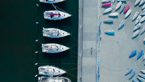 aerial top down shot of person walking on jetty on marina of gdynia with anchored boat