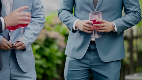 공식 의상 을 입은 사람 들 이 은 음료 의 컵 을 들고, 축제 나 모임 에서 야외 에 서 있다