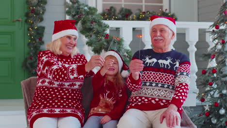 Senior-family-couple-grandmother-grandfather-with-granddaughter-holding-lit-Bengal-lights-sparkler