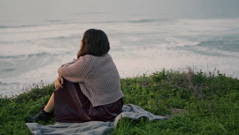 lonely brunette sitting blanket with book looking gloomy seascape. romantic girl