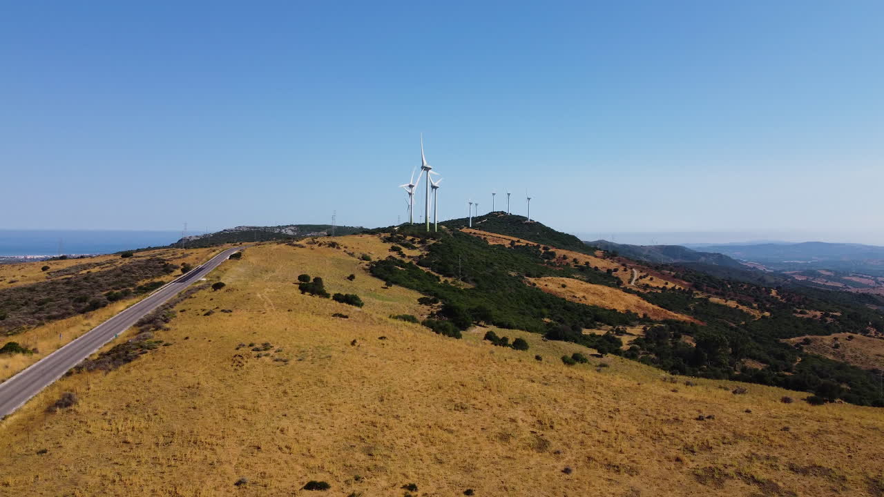 дрон направляется к дороге, ведущей к ветряной электростанции и вращающимся турбинам в горах недалеко от эстепоны, испания