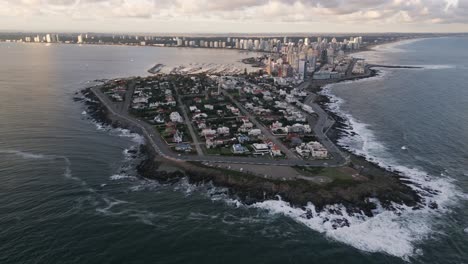 drone-above-Punta-del-Este-city-and-coastline,-Uruguay,-cityscape-modern-skyline-at-sunset
