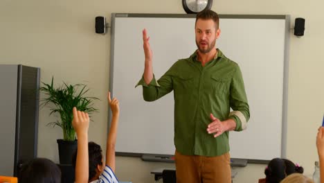 multi-ethnic schoolkids raising hands while sitting at desk in a classroom at school 4k