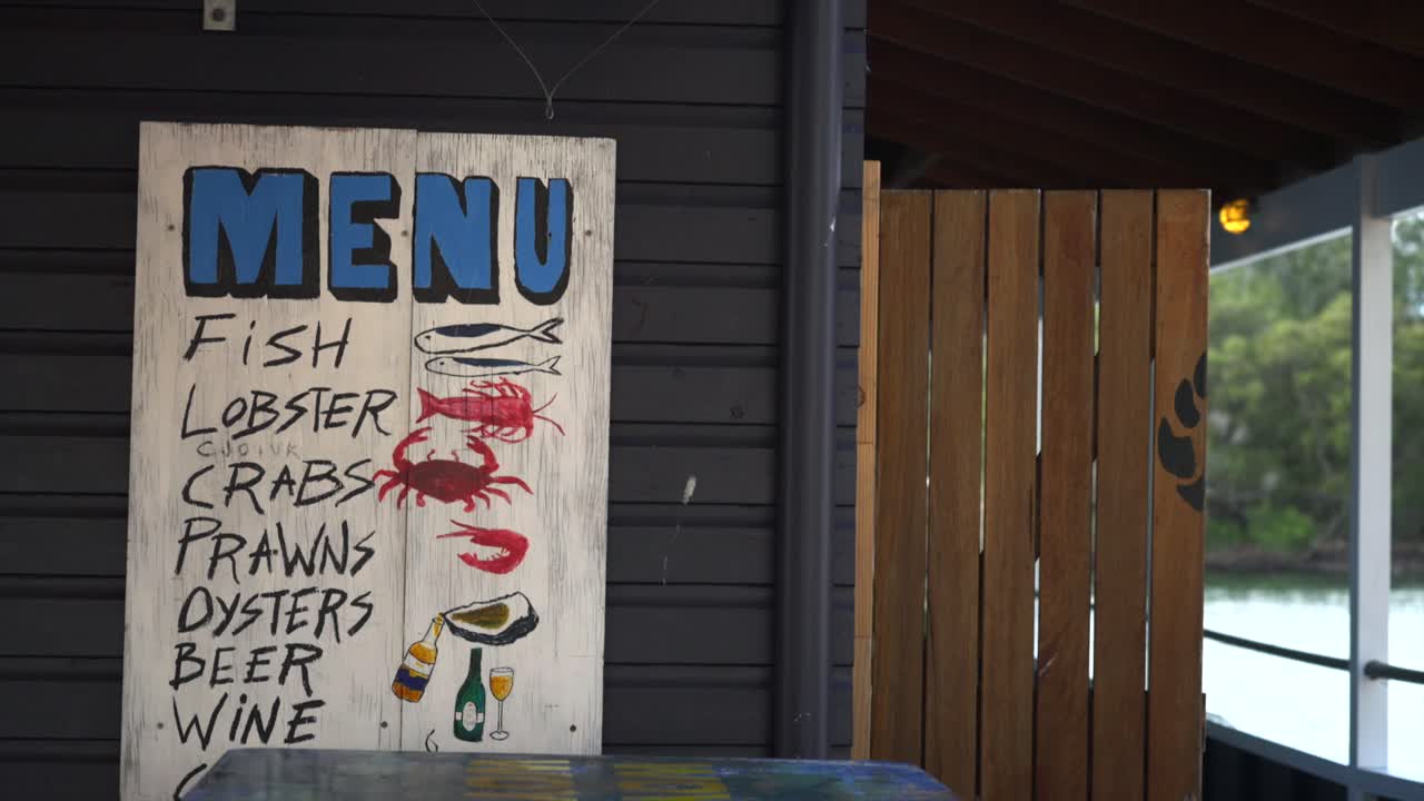 Håndmalet skilt med skaldyrsmenu på en restaurants ydermur.