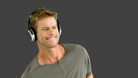 attractive man with headphones listening to music on grey screen