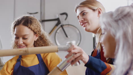 multi-cultural team of trainees in workshop assembling hand built bicycle frame together