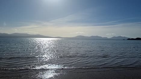 Slow-motion-shimmering-Irish-Seascape-from-Newborough-beach-shoreline-to-hazy-Snowdonia-mountain-range