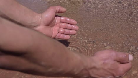 man hand cupped to catch fresh water from lake in the desert of ouarzazat morocco
