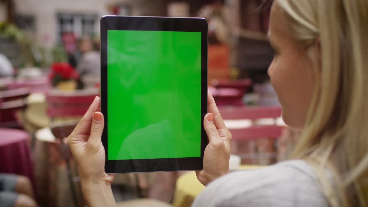 la chica sostiene una tableta pc en modo retrato en una cafetería al aire libre