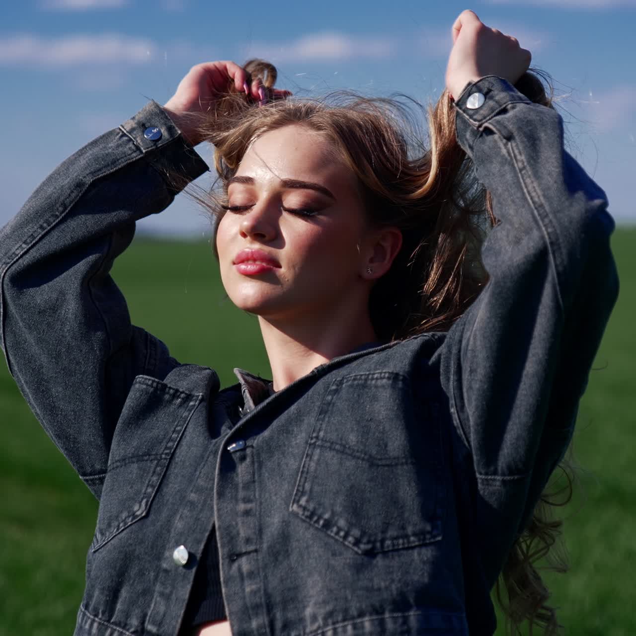 Portrait of a sexy model outdoors. Beautiful young woman posing on camera on the background of green field. Attractive girl in the countryside