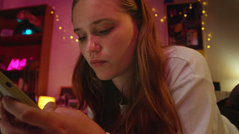 young woman texting on her phone in a bedroom