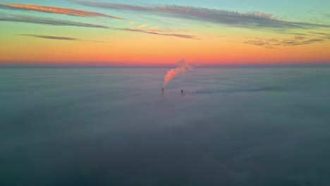 aerial view of industrial smokestacks in a foggy sunset