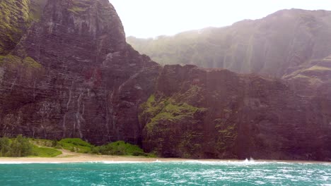 4k hawaii kauai boating on ocean left to right pan from tall rocky cliff to honopu arch in distance