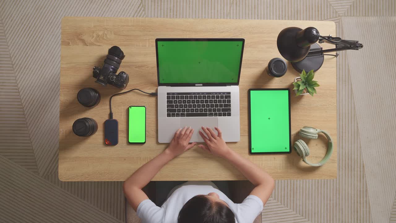 vista superior zoom en la toma de una mujer editor de video usando portátil de pantalla verde con pantalla verde teléfono inteligente y tableta al lado de la cámara en el espacio de trabajo en casa