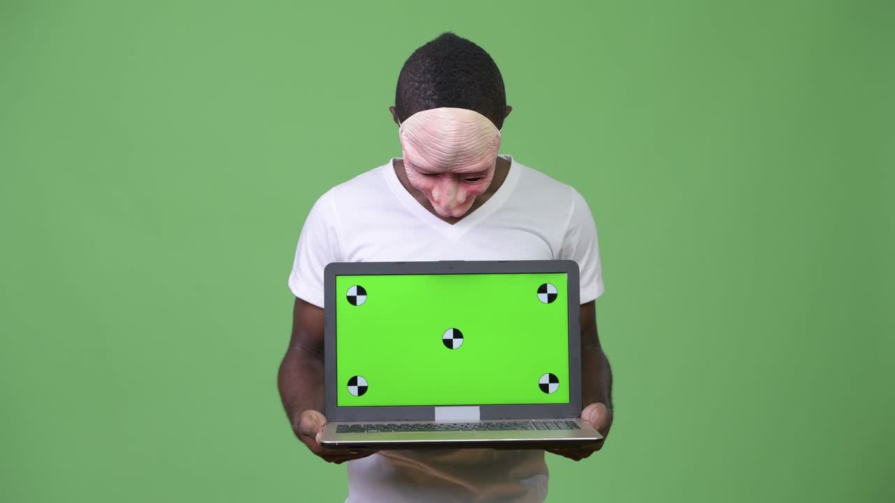Jovem homem africano usando máscara enquanto mostra o notebook