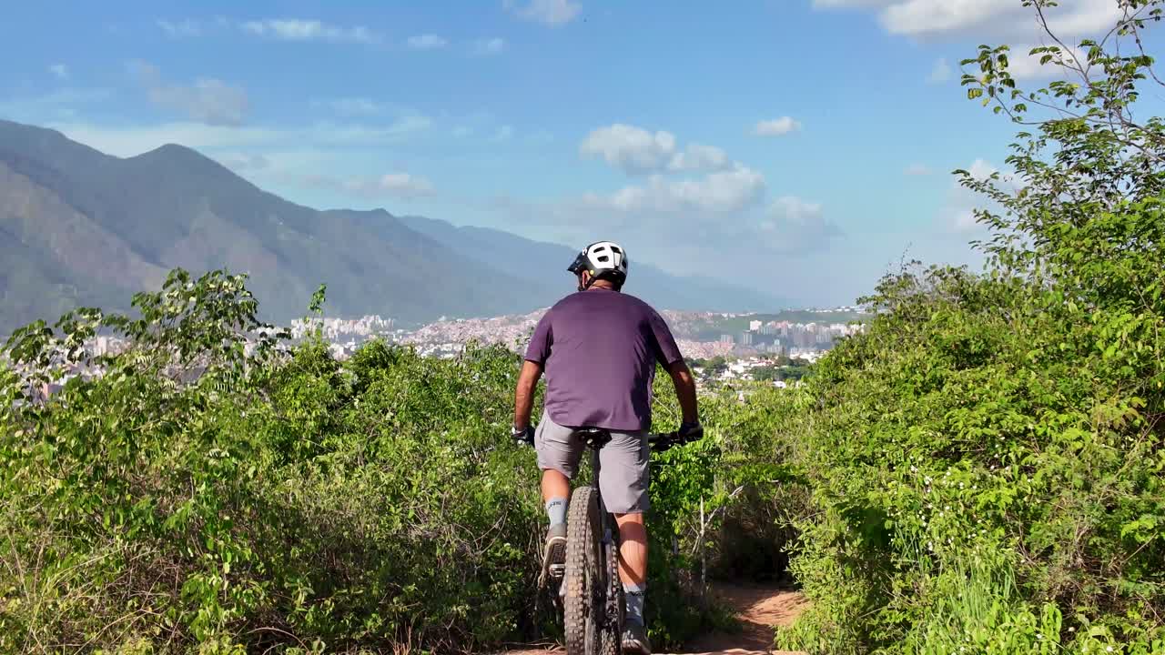 Mountain biker on a dirt trail with a scenic view of Caracas city and mountains. South America