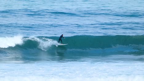 panning clip of surfer riding a waves blue ocean in europe beach