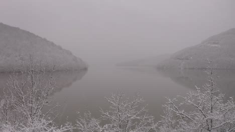 overcast and snowing day by lake drone push in shot