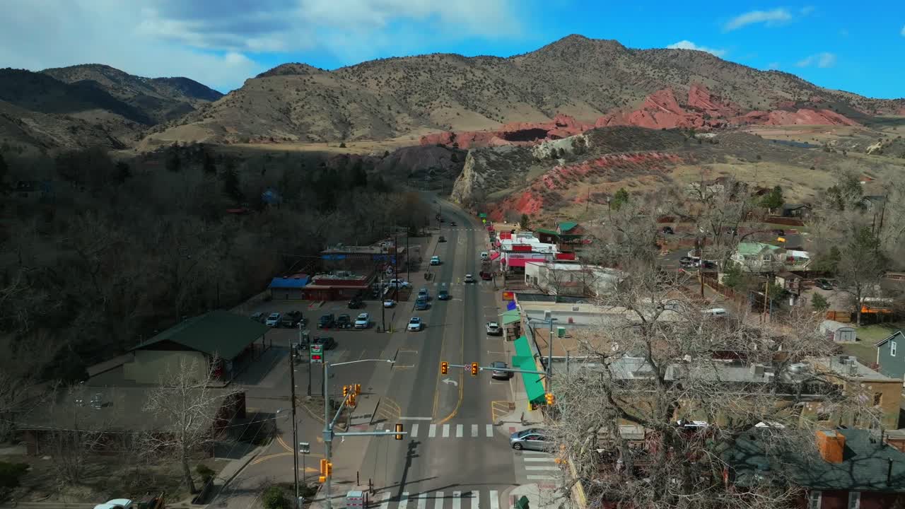 Mid Winter downtown Main Street Morrison Colorado aerial drone Red Rocks Park and Amphitheater Mount Morrison Bear Creek sunny blue sky high clouds traffic car driving forward pan up motion