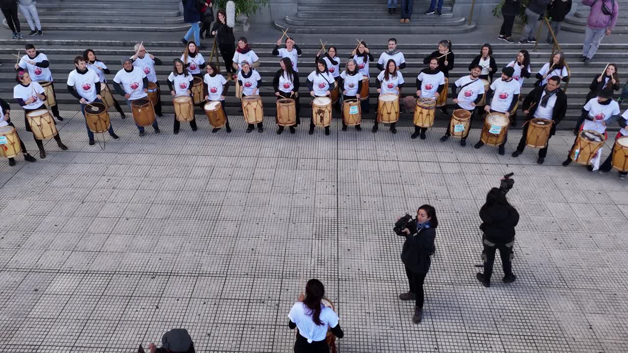 Percussion band plays rhythmic in front of iconic Kirchner Cultural Center in Buenos Aires, Argentina, Slow-motion, Aerial drone at low altitude
