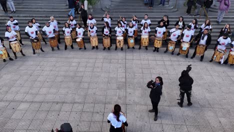 percussion band plays rhythmic in front of iconic kirchner cultural center in buenos aires, argentina, slow-motion, aerial drone at low altitude