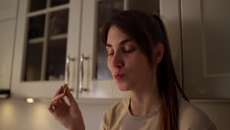 woman eating snack in kitchen