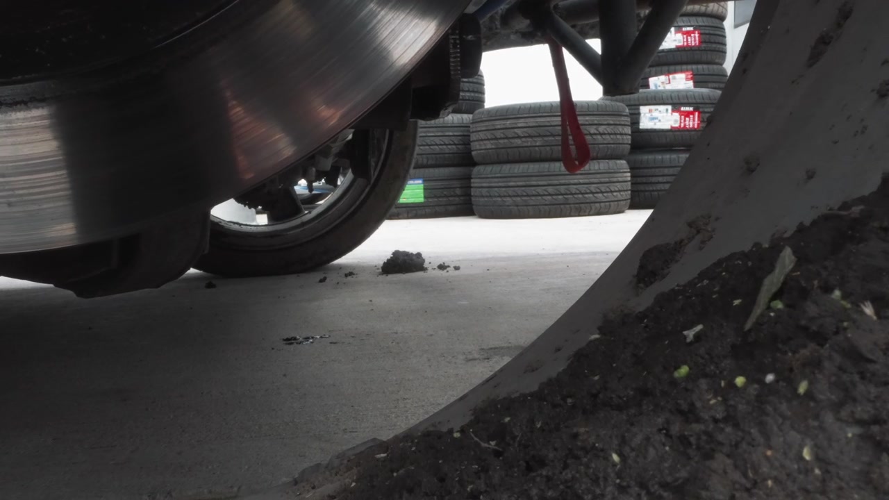 Low Angle View of a Dirty Car Wheel and Brake Disc in a Garage