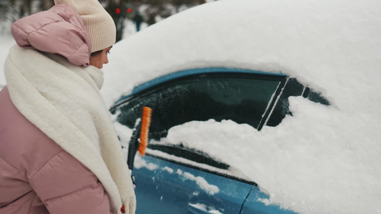 mujer quitando la nieve del coche en invierno
