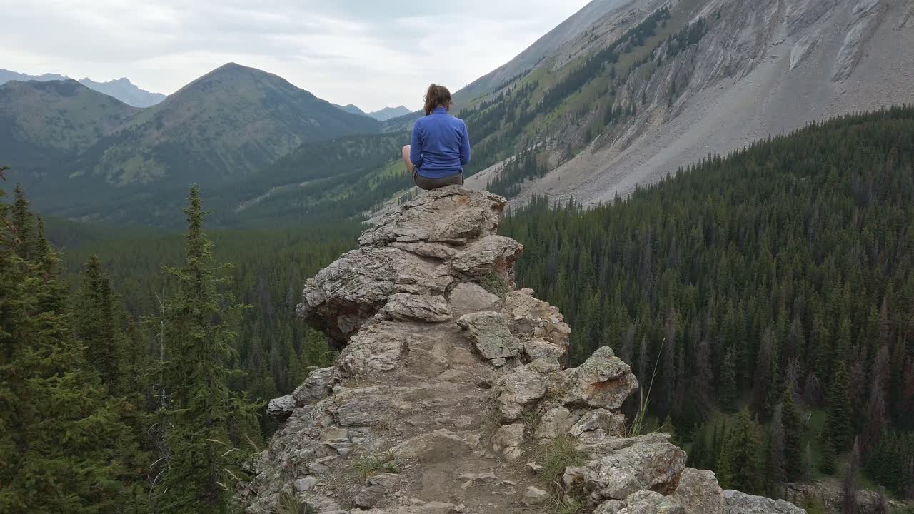 caminante sentado leyendo en la cornisa se acercó a las montañas rocosas de kananaskis, alberta, canadá