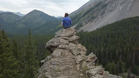 hiker sitting reading on ledge approached rockies kananaskis alberta canada