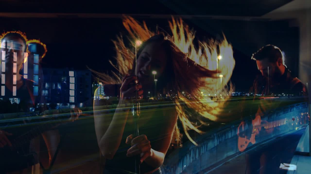 Female vocalist gripping mic and performing, band playing while city light trails overlaying stage