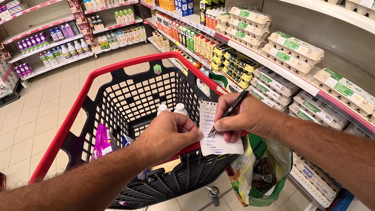 Persona che spunta gli articoli da una lista della spesa in un supermercato.