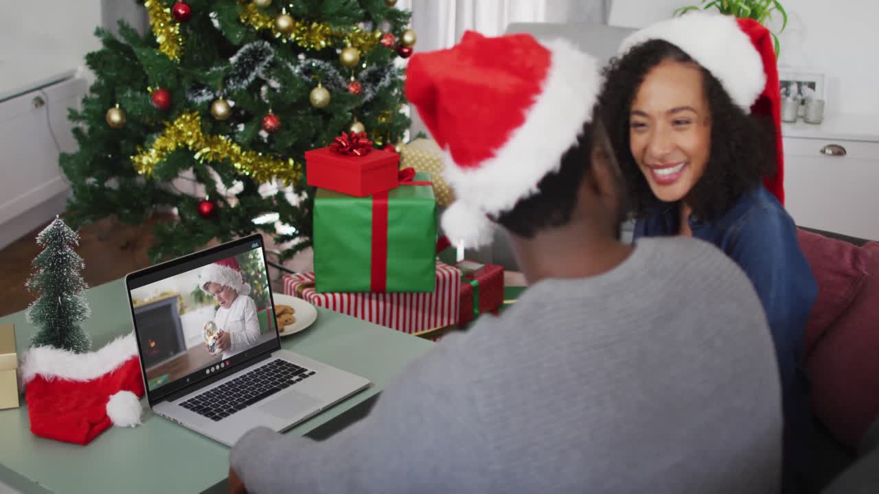 feliz pareja afroamericana en videollamada en portátil con un niño en el sombrero de santa en tiempo de navidad