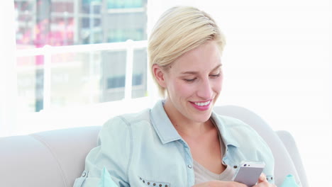 una mujer rubia usando su teléfono móvil.