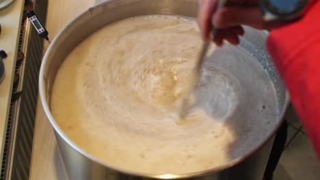 Time-lapse-of-the-mash-in-process-of-a-home-brewed-beer-with-one-person-pouring-in-the-malt-and-another-steering-the-liquid