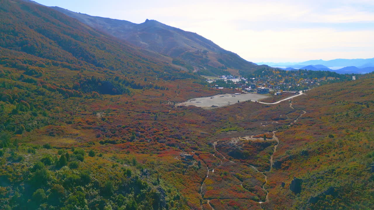 Vista aérea de un valle otoñal colorido con un pueblo y un lago distantes