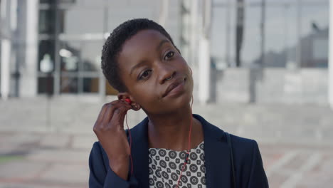 Retrato-Exitoso-Joven-Mujer-De-Negocios-Afroamericana-Se-Pone-Auriculares-Escuchando-Música-Sonriendo-Disfrutando-De-Un-Estilo-De-Vida-Urbano-Relajado-En-Cámara-Lenta-De-La-Ciudad