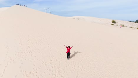aerial view of a girl standing and walking on the hill in the desert.