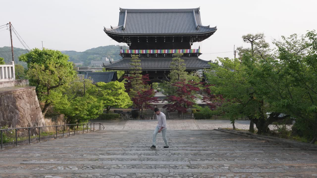 Giovane uomo caucasico che sale le scale di pietra al tempio Konkai Komyoji, Kyoto, Giappone