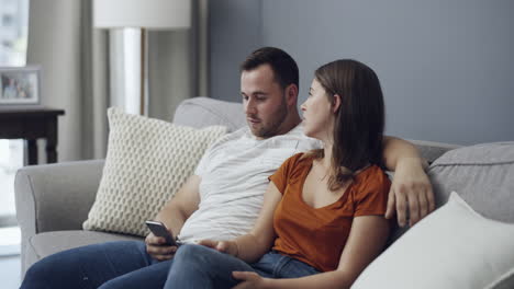 una pareja discutiendo en un sofá.